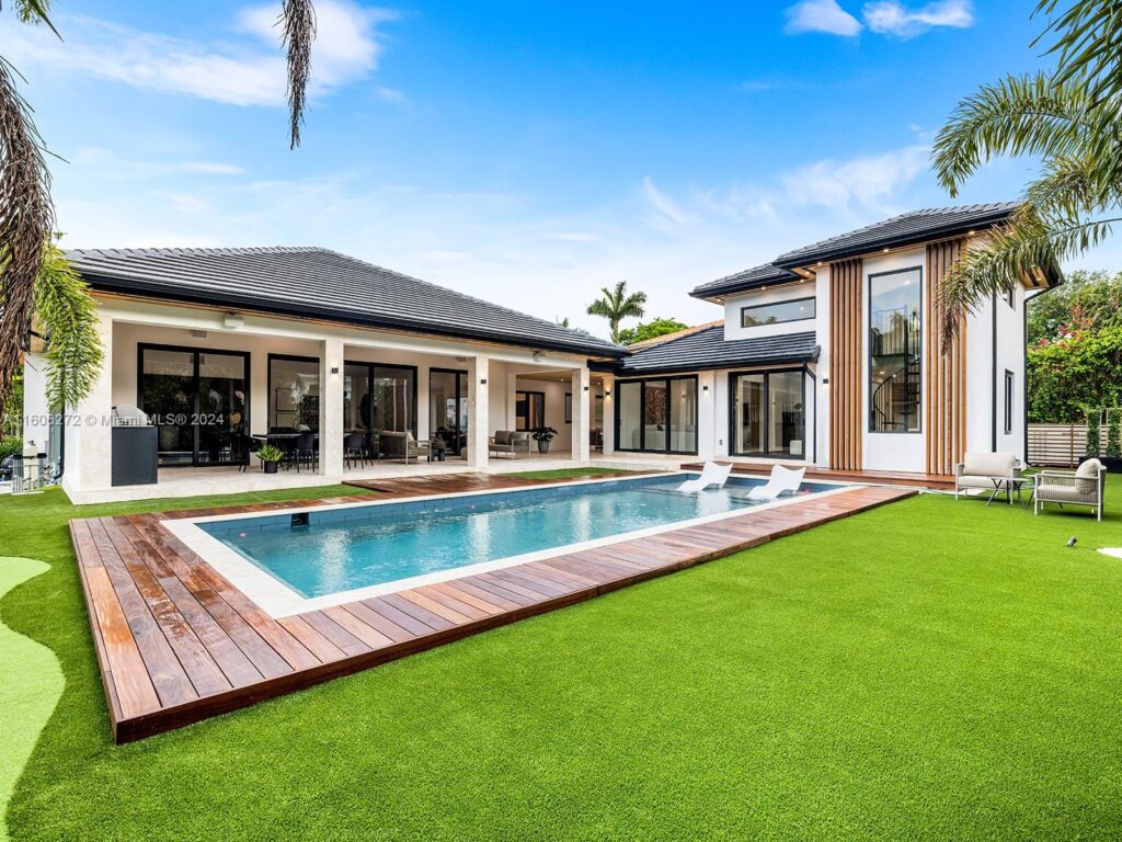 Contemporary Miami home with outdoor kitchen, modern pool, and artificial turf